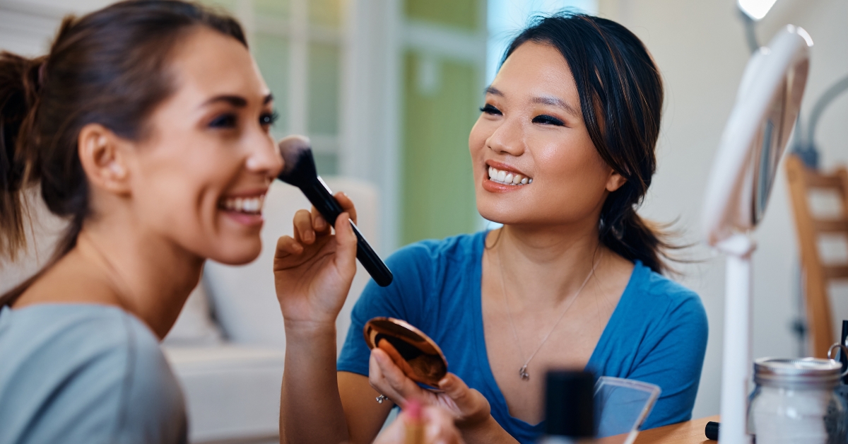 woman applying blush on female friend's cheek