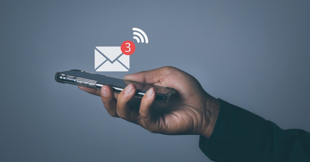 man holding smartphone with email notification pop up over grey background