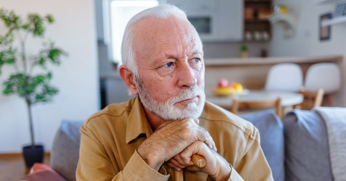 senior man sitting in lounge on couch thinking about something serious 