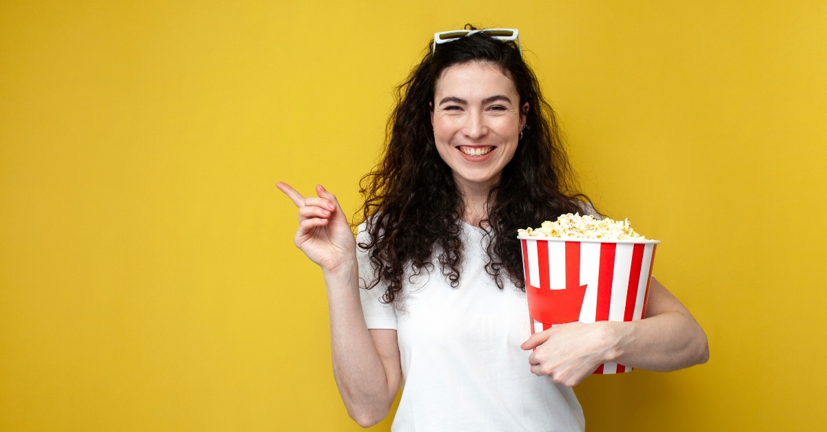 smiling woman holds large bucket of popcorn