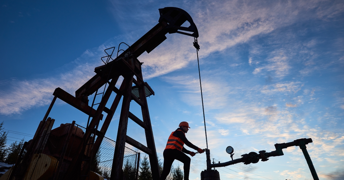  engineer in work vest and helmet working on petroleum pump jack