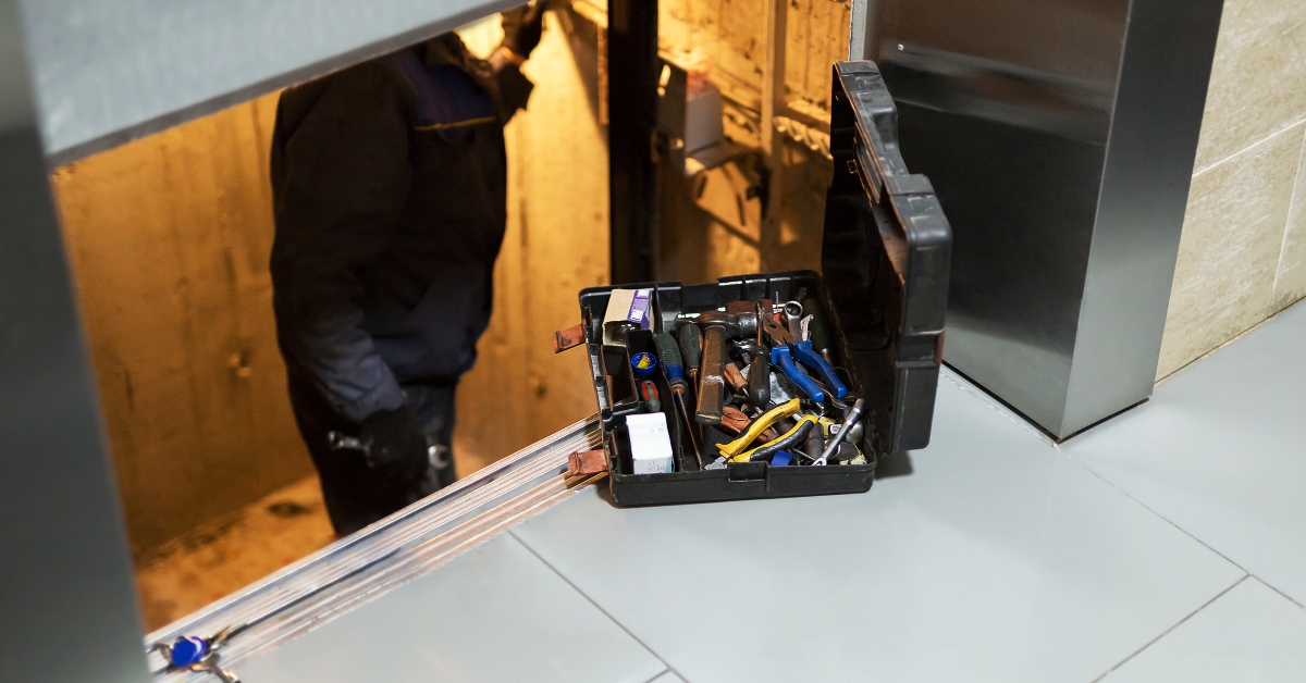 specialist adjusting lift mechanism in elevator shaft