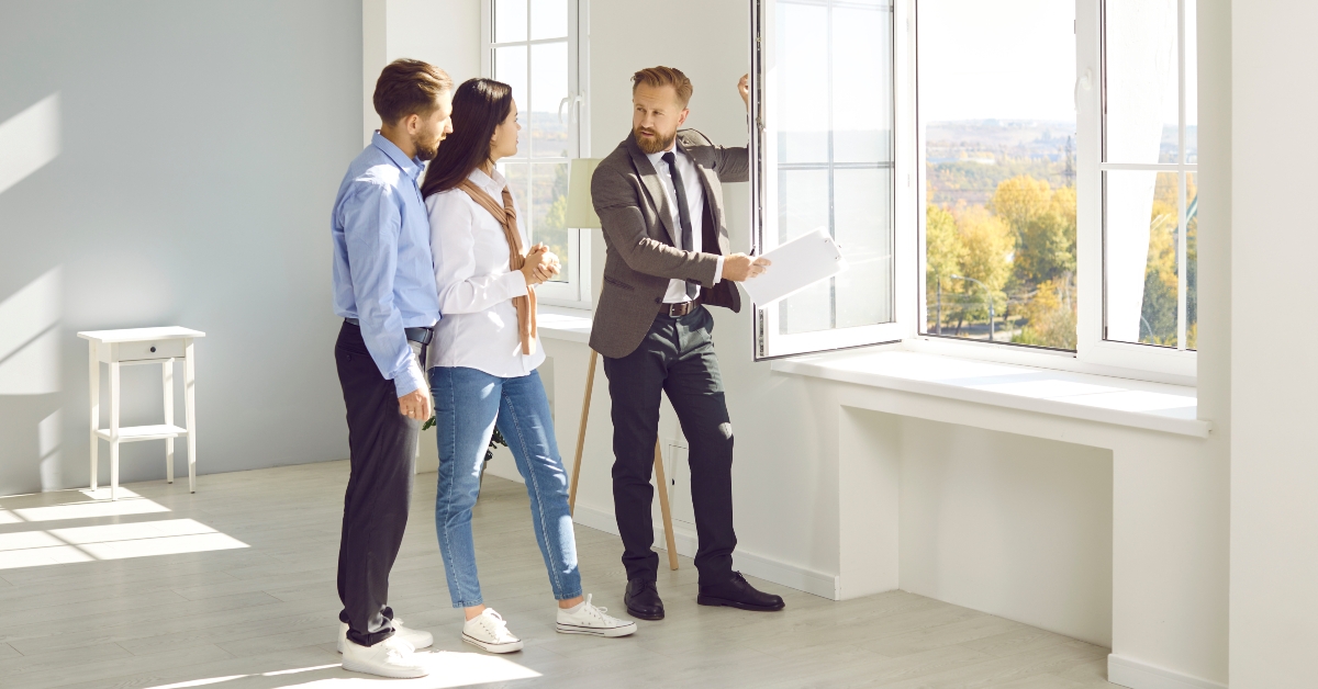 realtor in suit with documents in his hands advises young couple