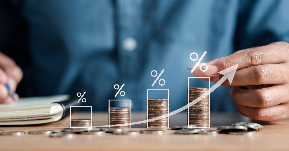 man stacking coins on wooden table with 3d percentages and graphs showing dividend concept