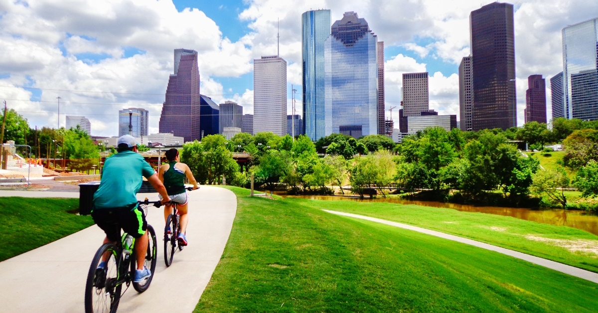 couple cycling on a paved trail in houston during the day