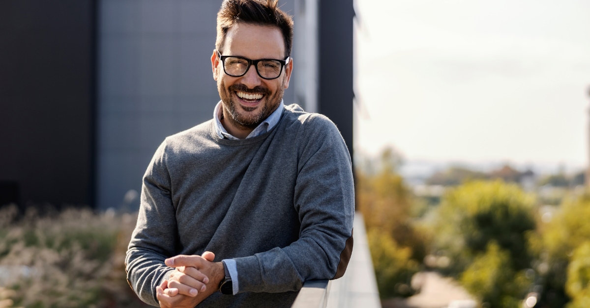 attractive businessman standing on terrace at office posing for camera