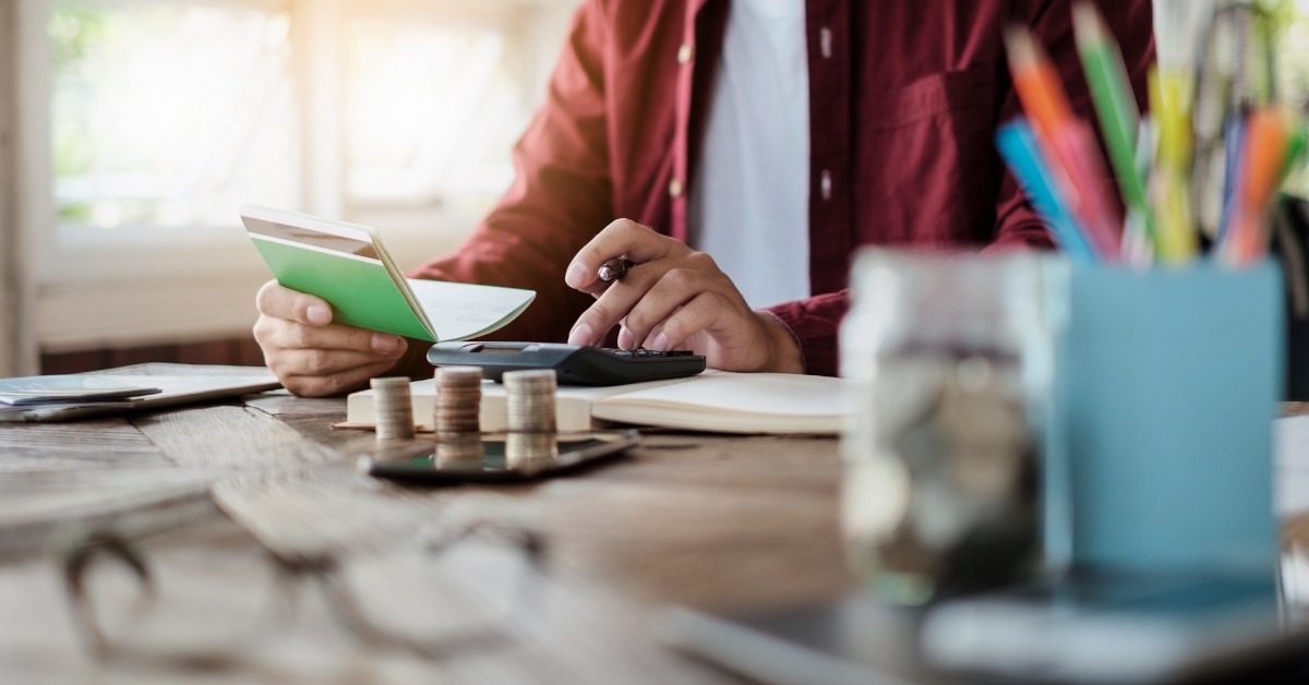 businessman sitting at table with stack of pennies and notebook in hand