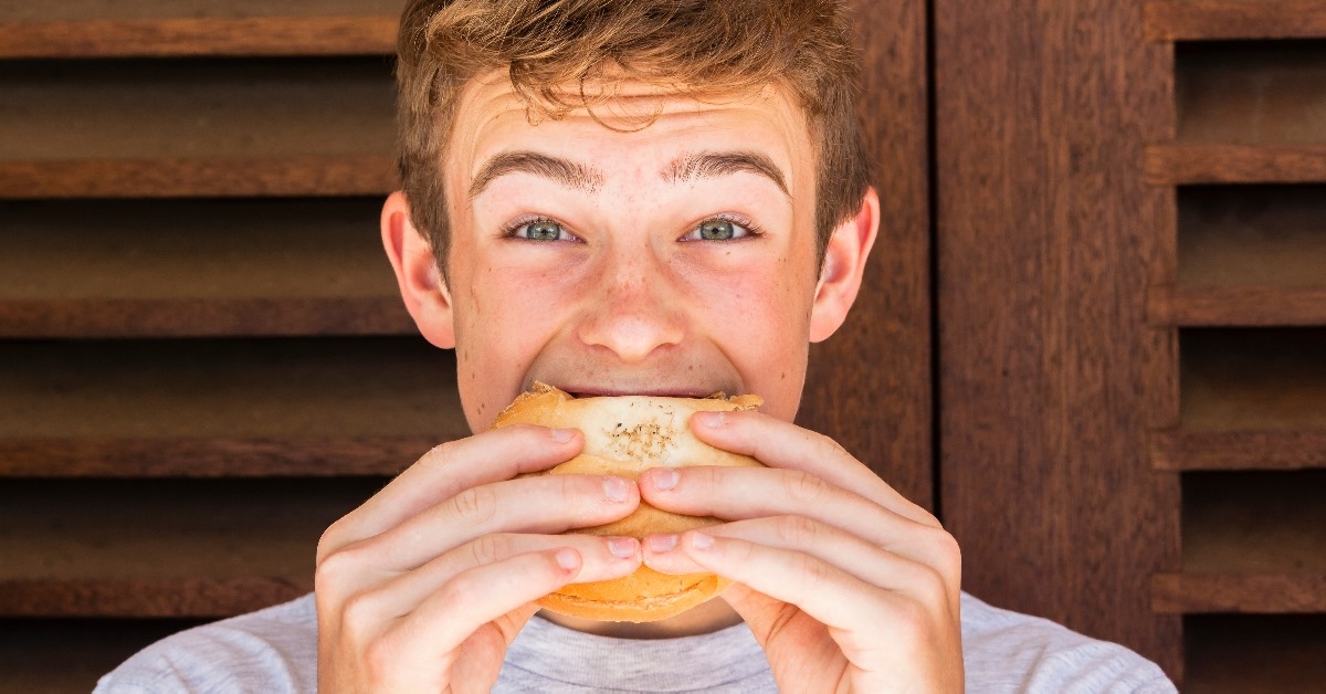 man taking a bite of a burger