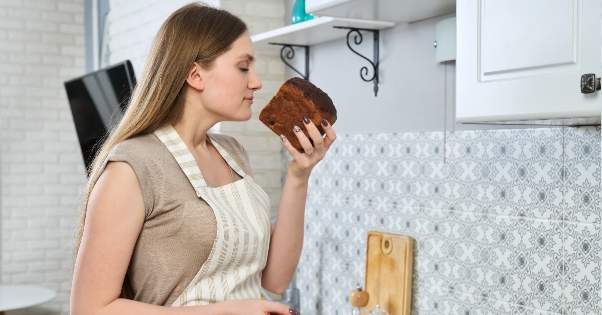 woman standing in kitchen at home getting fascinated by the smell of fresh rye bread
