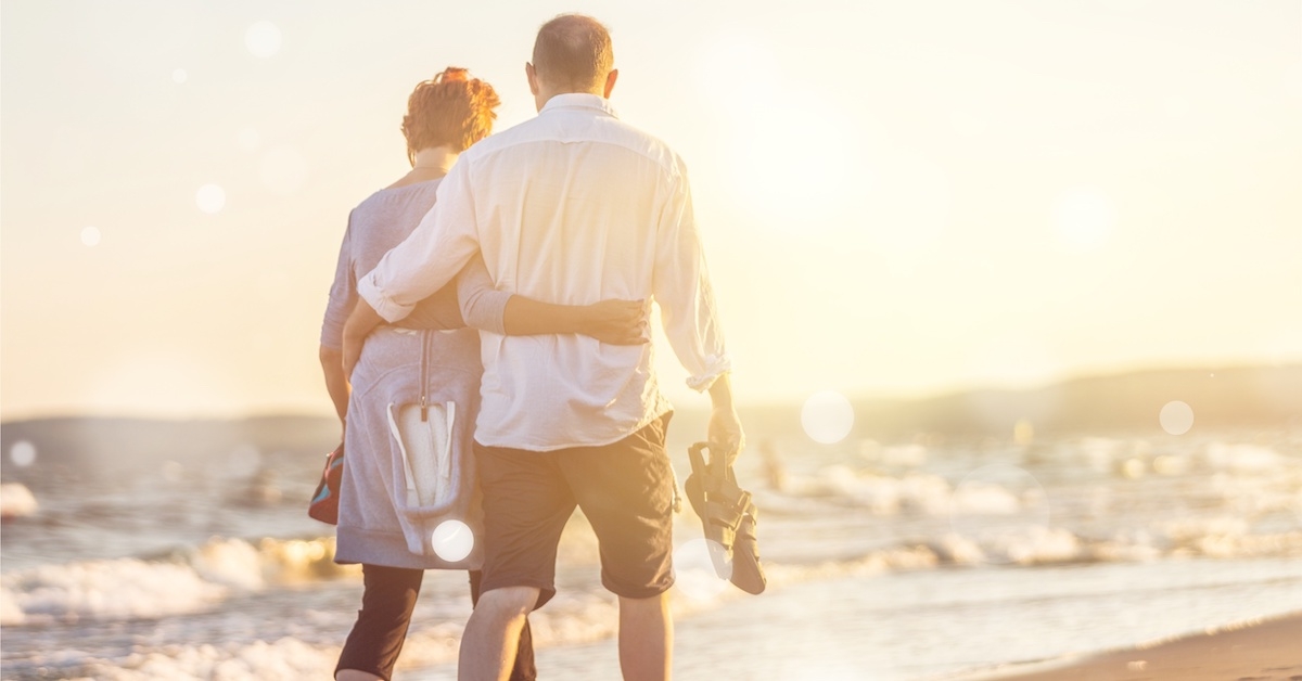 A man and a woman walk down the beach in an embrace