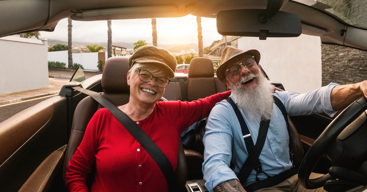 happy senior couple driving convertible car while on vacation