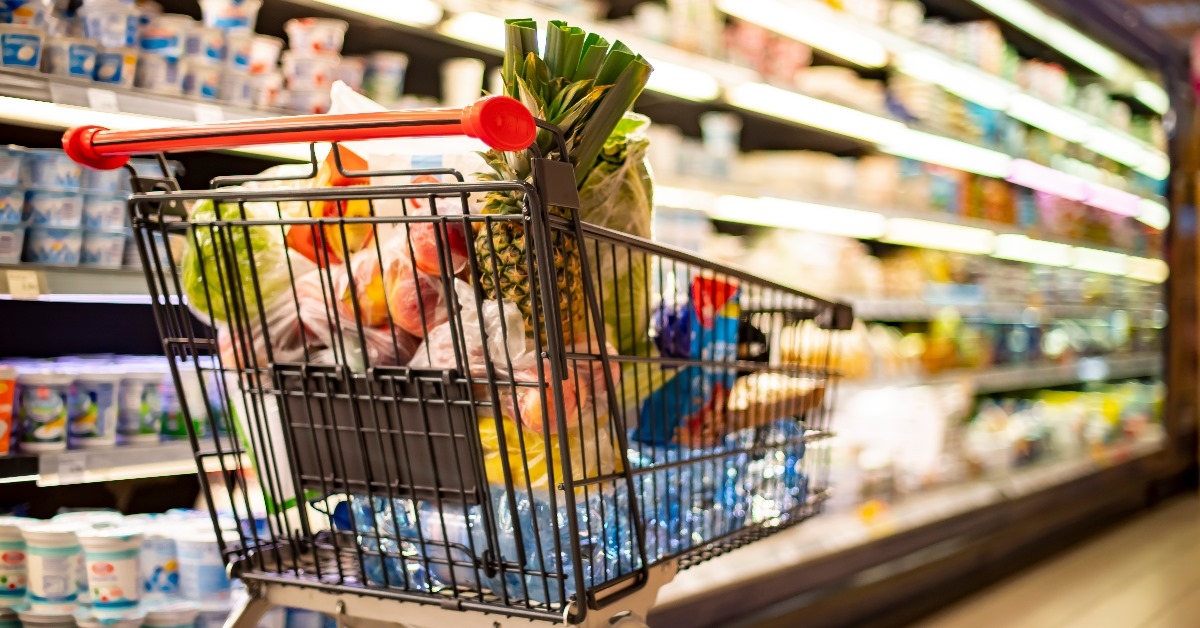 shopping trolley full of grocery standing inside supermarket 