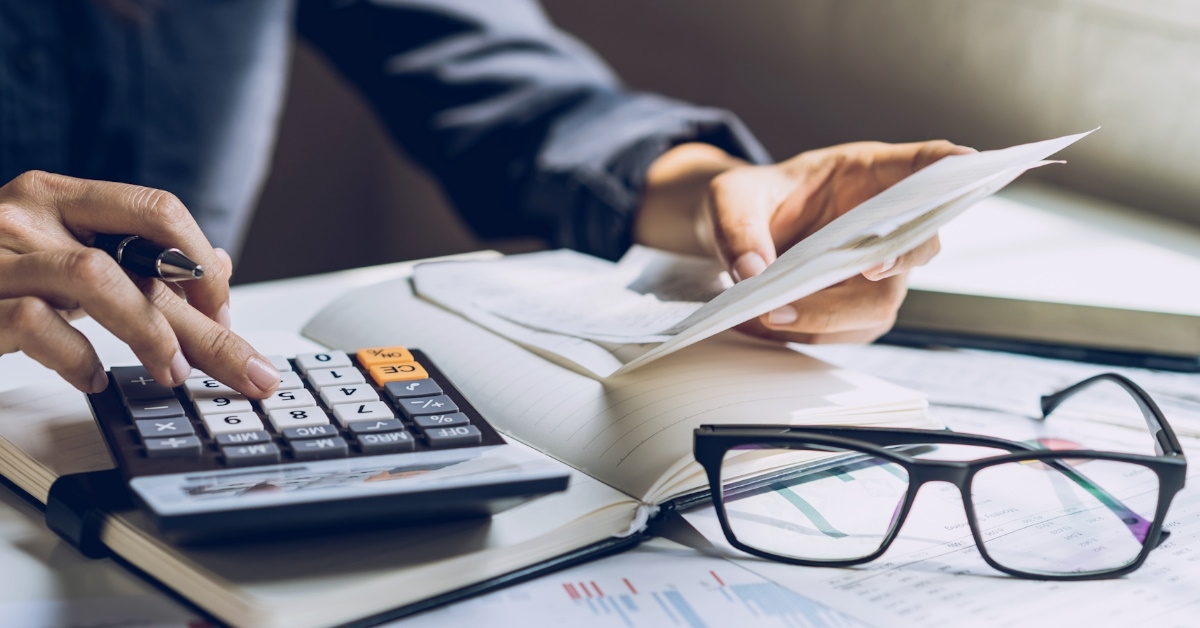 woman holding receipts in hand while using calculator to calculate expenses