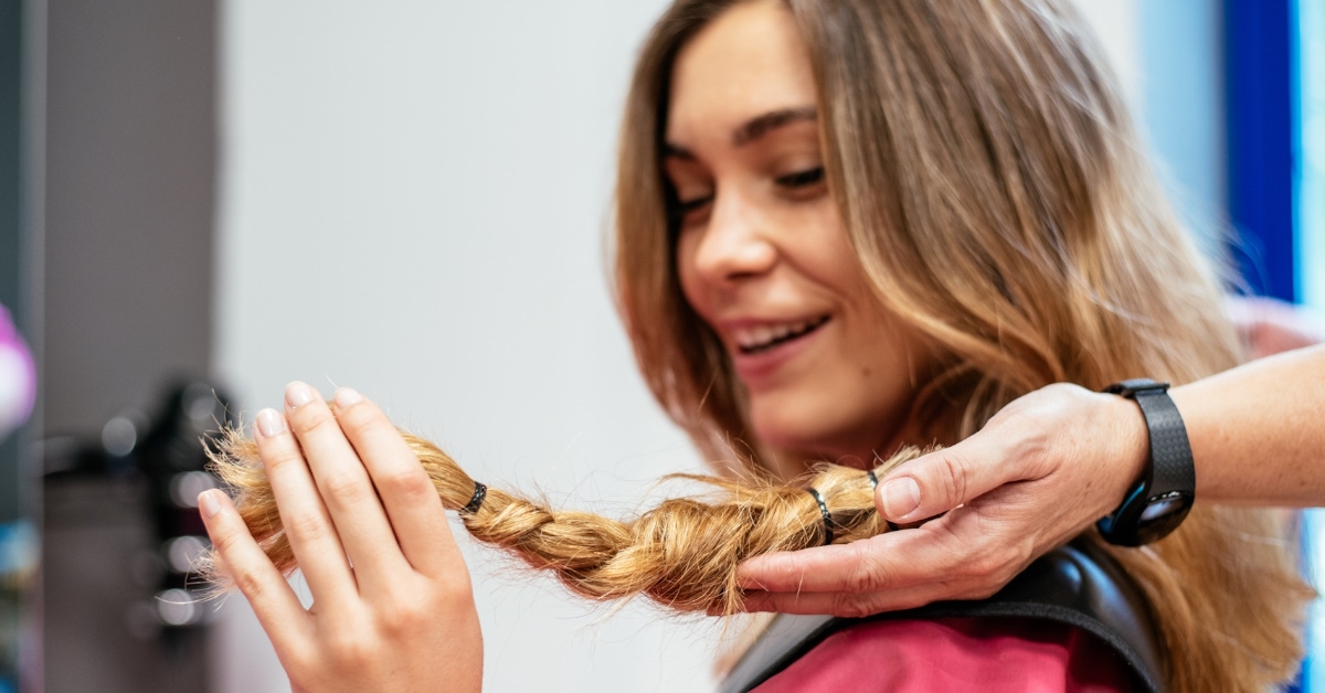 woman at hair salon cutting her hair short to donate it to cancer patients