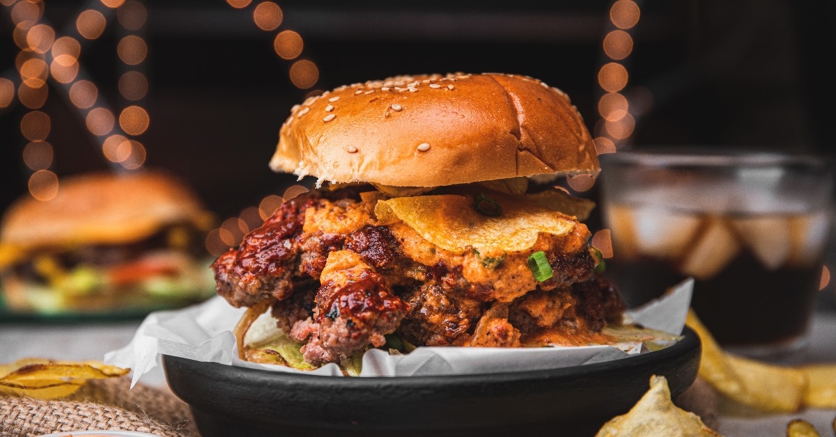 amazing american traditional smash burger with melted cheddar cheese, bacon, grilled onions and ice chilled cola