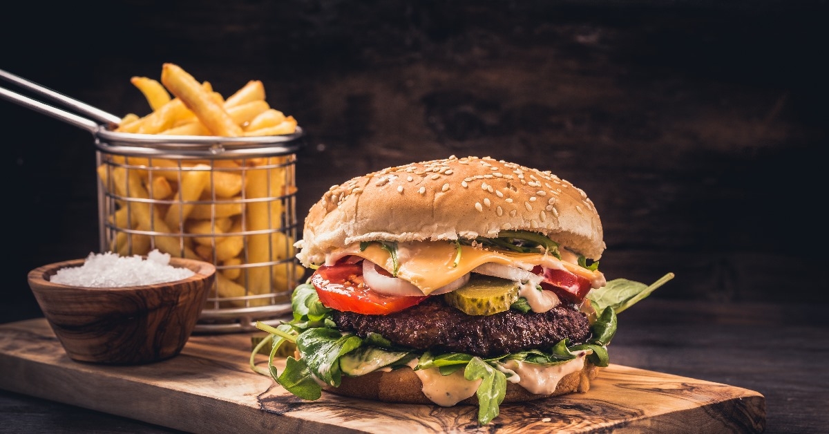 big juicy cheese burger with fries and sauce on a wooden tray 