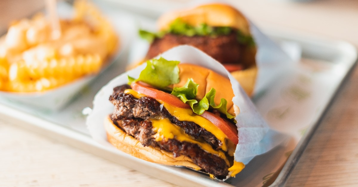 double cheeseburger with sliced tomato and fries served on silver tray 