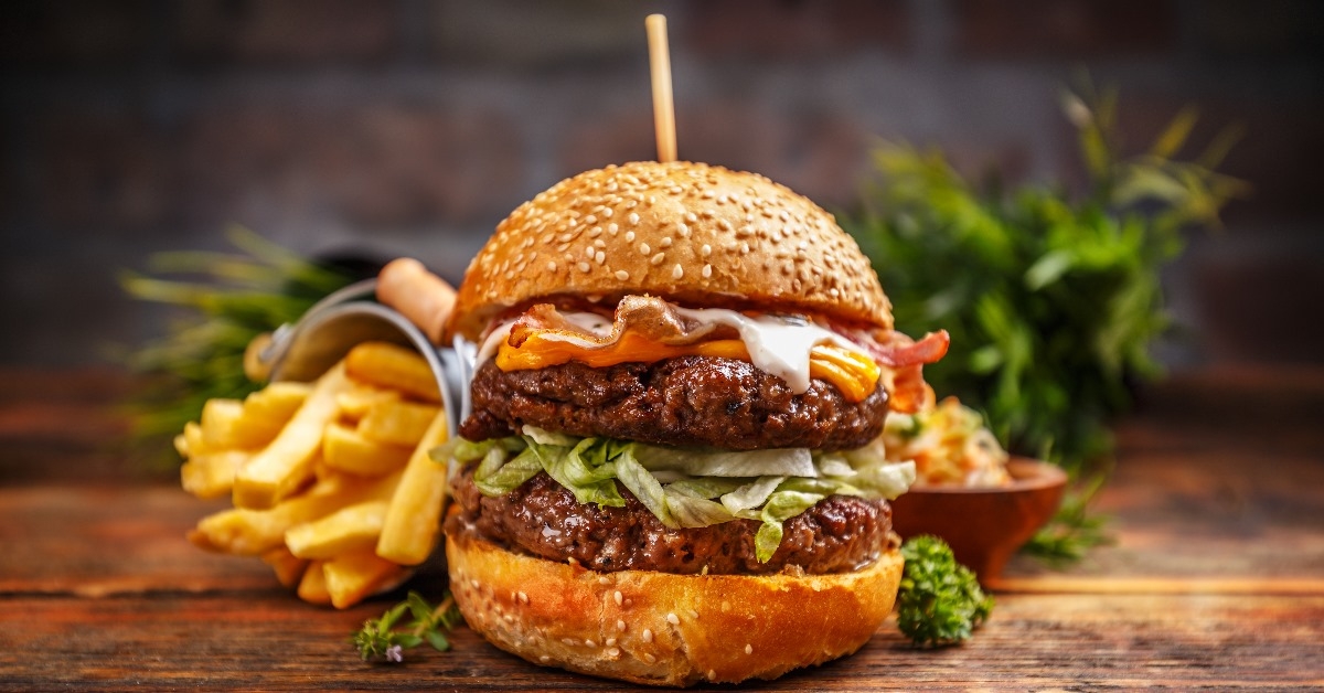 A big fresh burger with two patties and cheese and french fries.