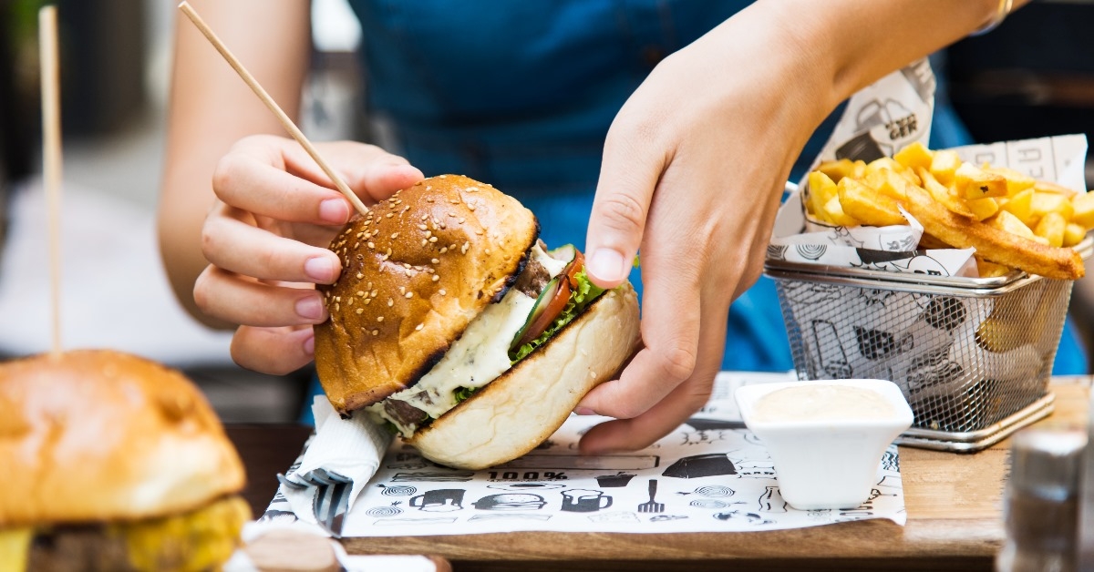 girl picking her burger to eat from the wooden tray
