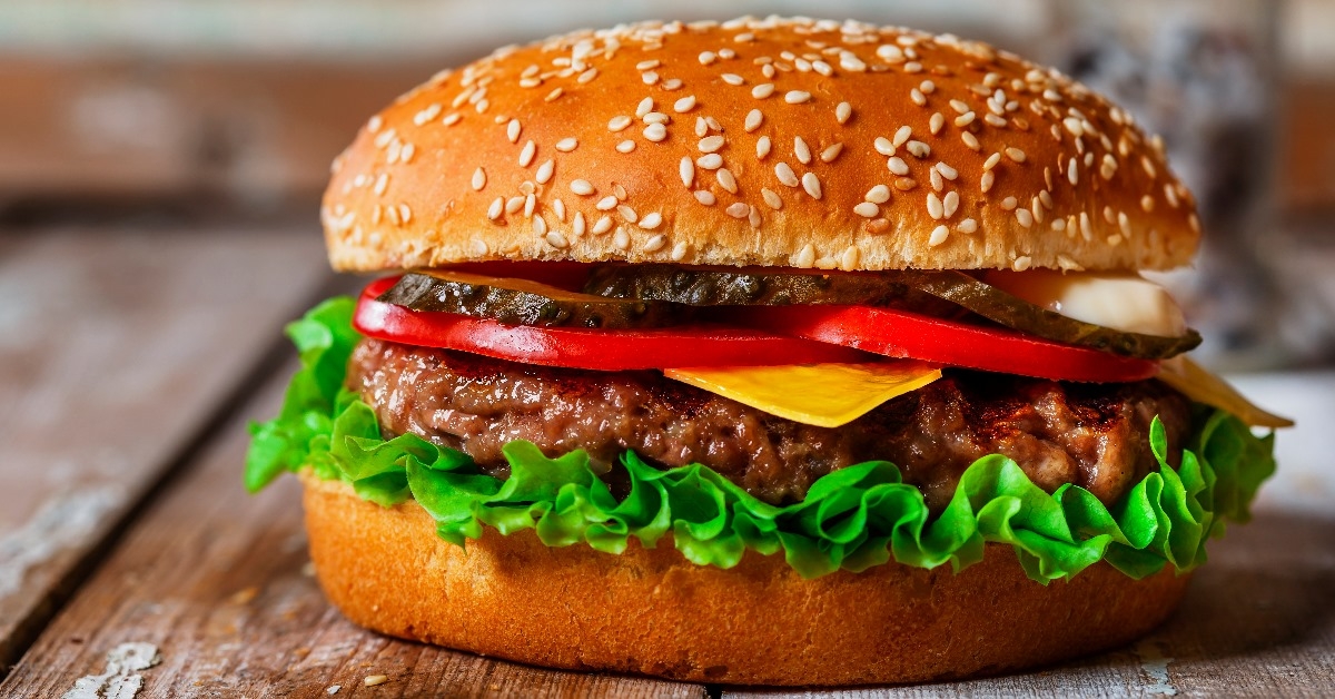 hamburger with cutlet grilled,lettuce and sliced vegitables on a wooden surface