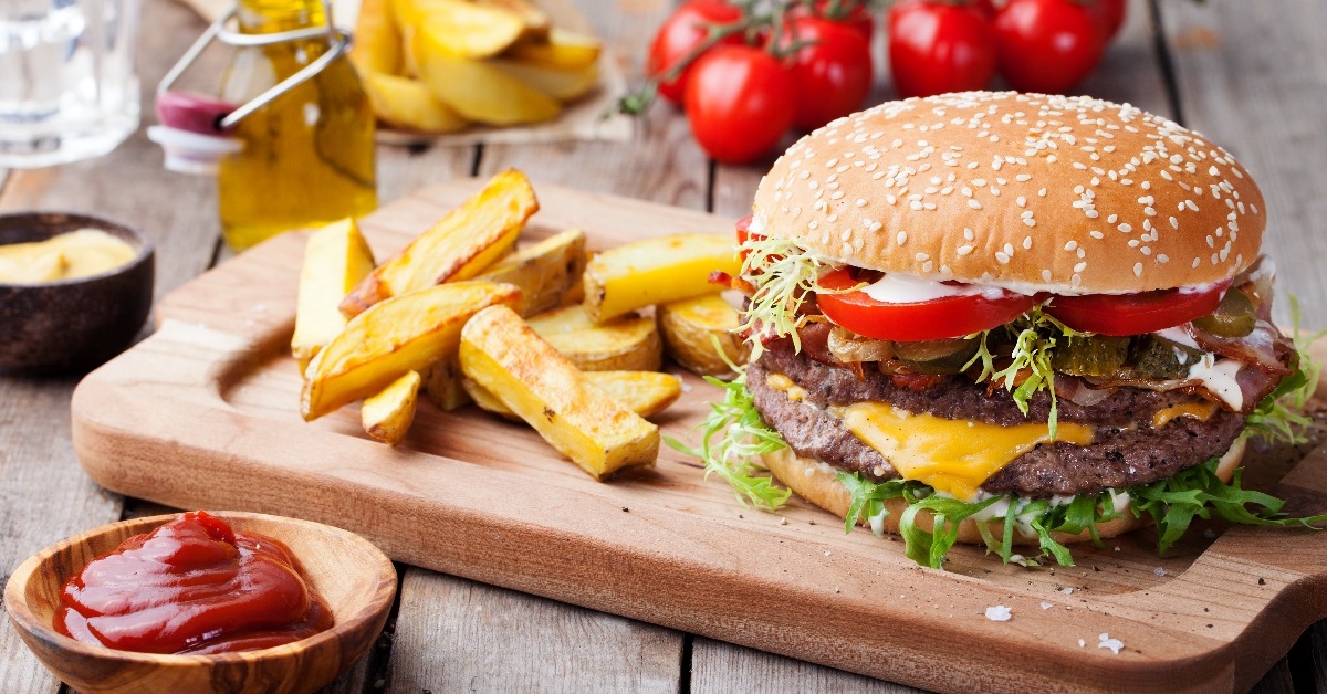 hamburger with french fries on the brown serving tray along with ketchup and sauce