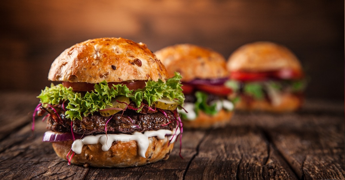 juicy beef burgers with sliced vegitables on a wooden table
