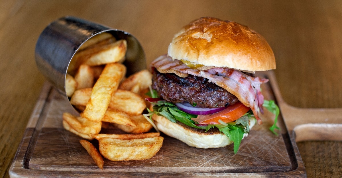 tasty burger with bacon and fries on the table of a restaurant.