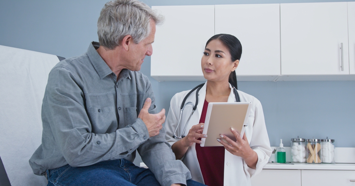 asian woman doctor talking to a senior male patient