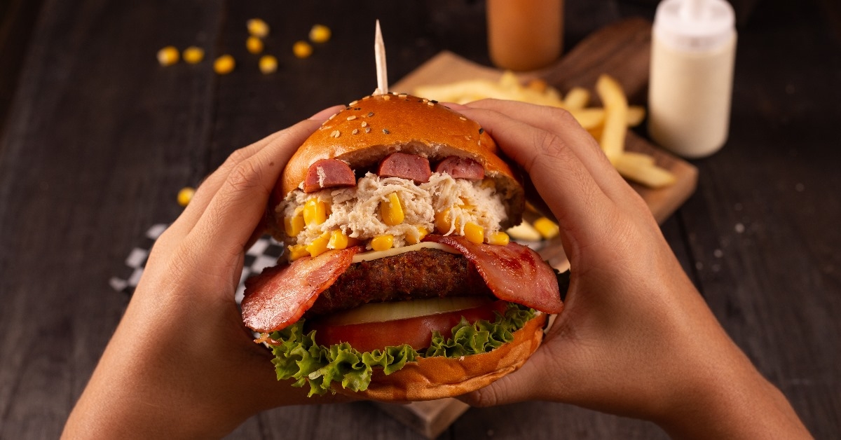 eating big burger with corn and chorizo
