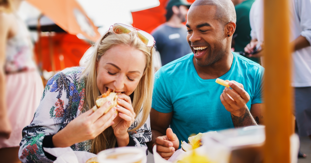couple having fun time eating burgers and drinking beer