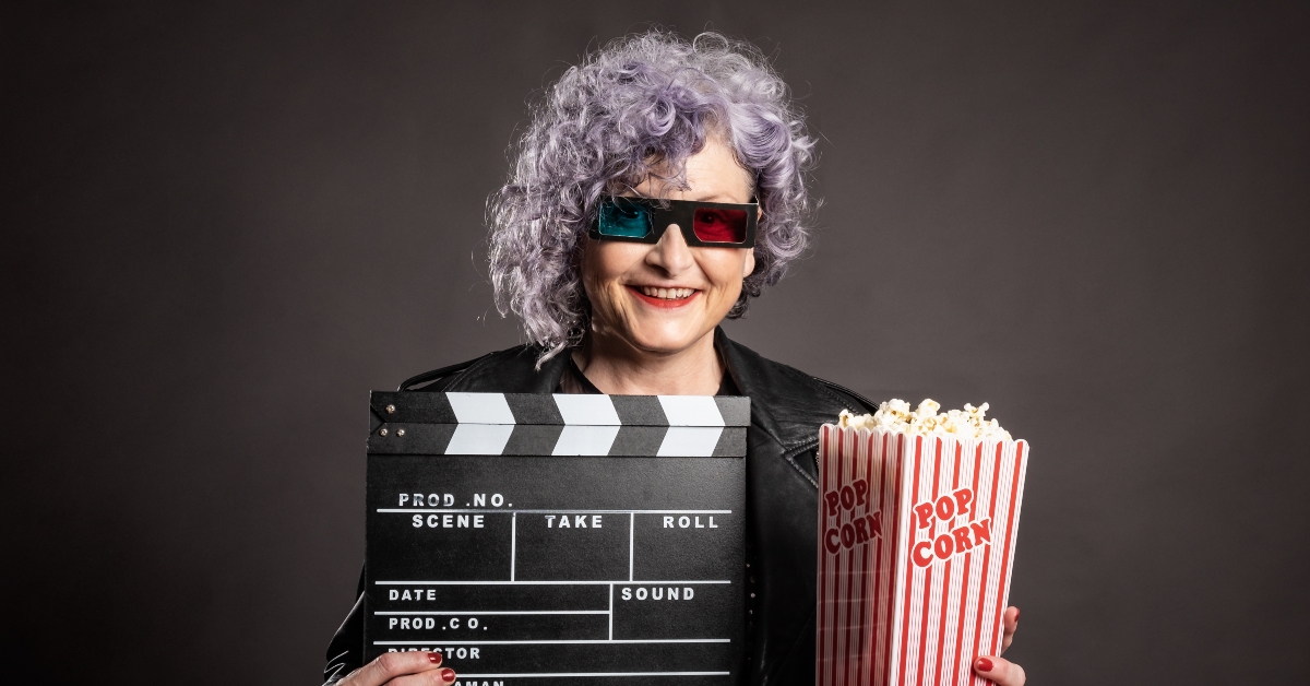 older woman holding popcorn and movie clapper