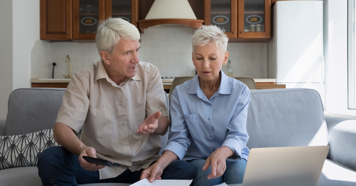 senior couple pensioners check bills using laptop