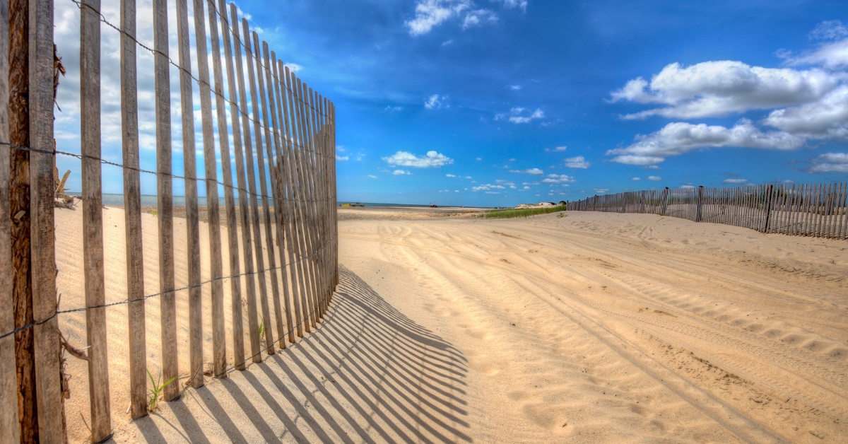 sandy beach path secured with fences under clear sky on sunny day