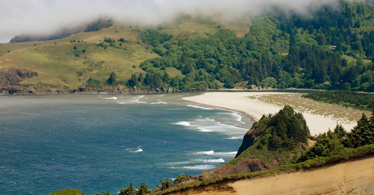 god's thumb at lincoln city oregon with cloud sky over blue water sandy shore