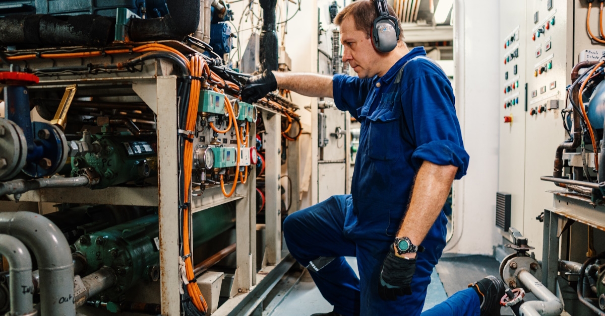 male technician sitting on floor performing onboard ship maintenance