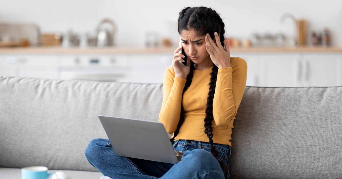stressed woman looking at laptop while talking on cellphone