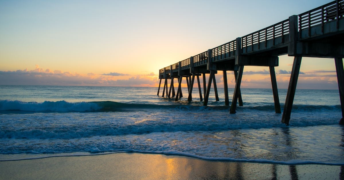 vero beach pier at sunset with water at shore
