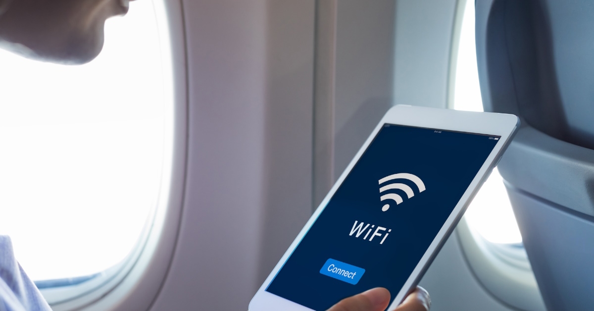 passenger holding tablet with wifi access sign while sitting on plane