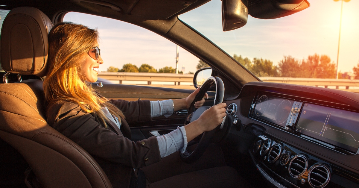 businesswoman driving car at sunset