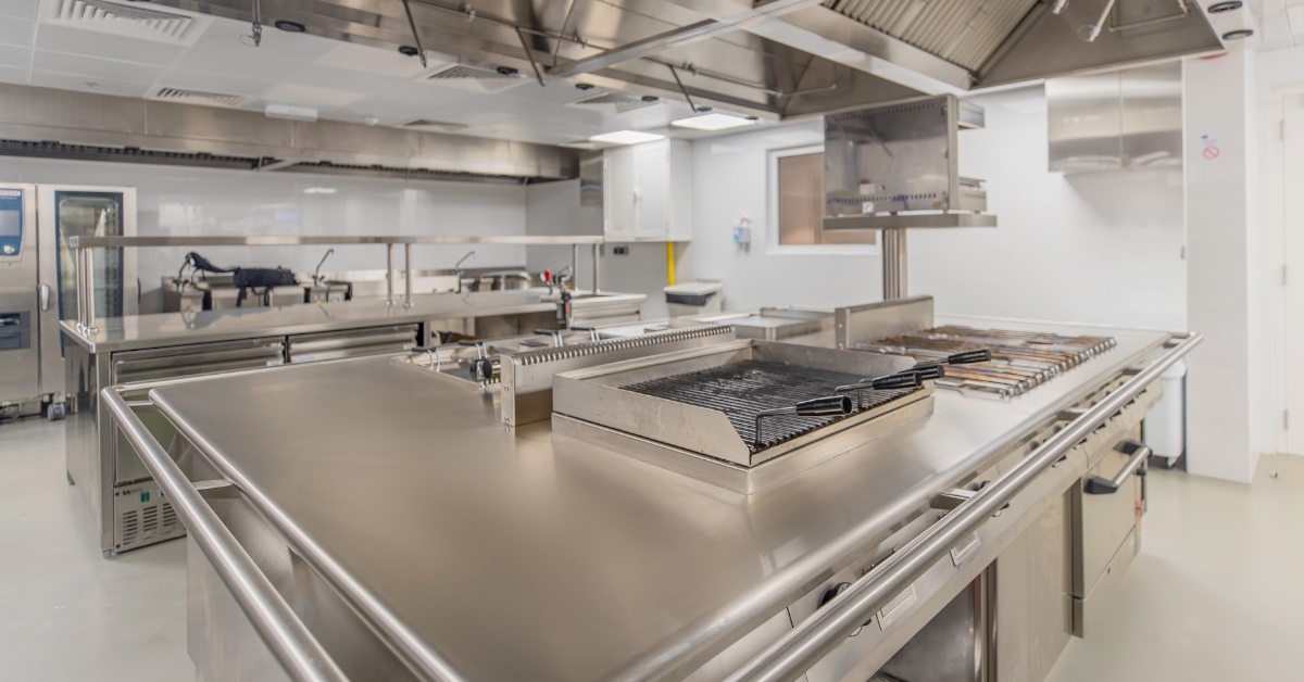 commercial kitchen with barbecue grills, stoves and oven.