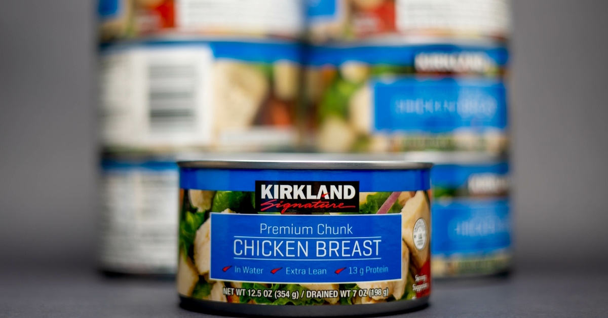 A can of Kirkland Signature Premium Chunk Chicken Breasts with many blurred cans in the background