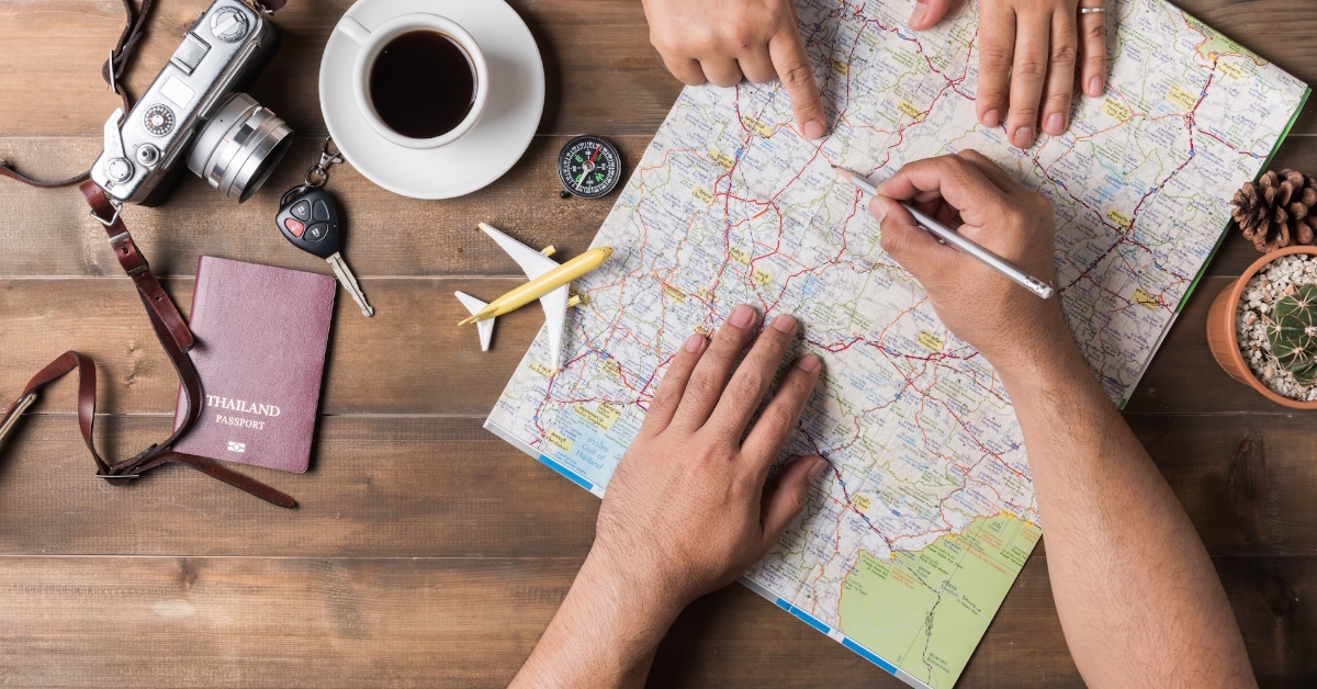 top view of young couple planning vacation trip with map sitting on a table. 