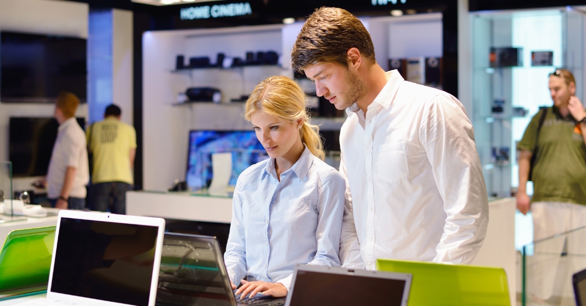 young couple checking laptop in electronic store 