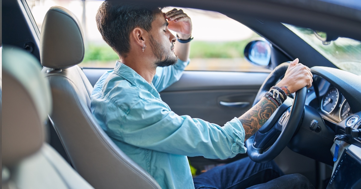 Young hispanic man is stressed while driving car because his car is cosuming too much fuel.