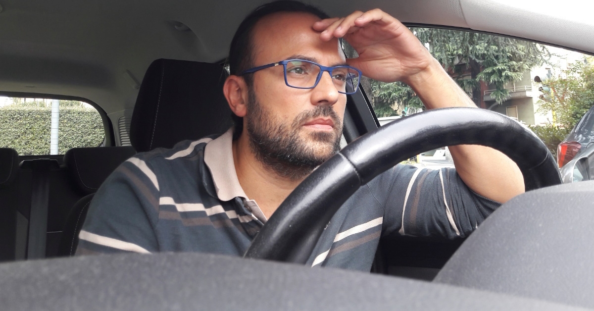 Middle aged man wearing glasses is waiting for traffic lights to turn green.