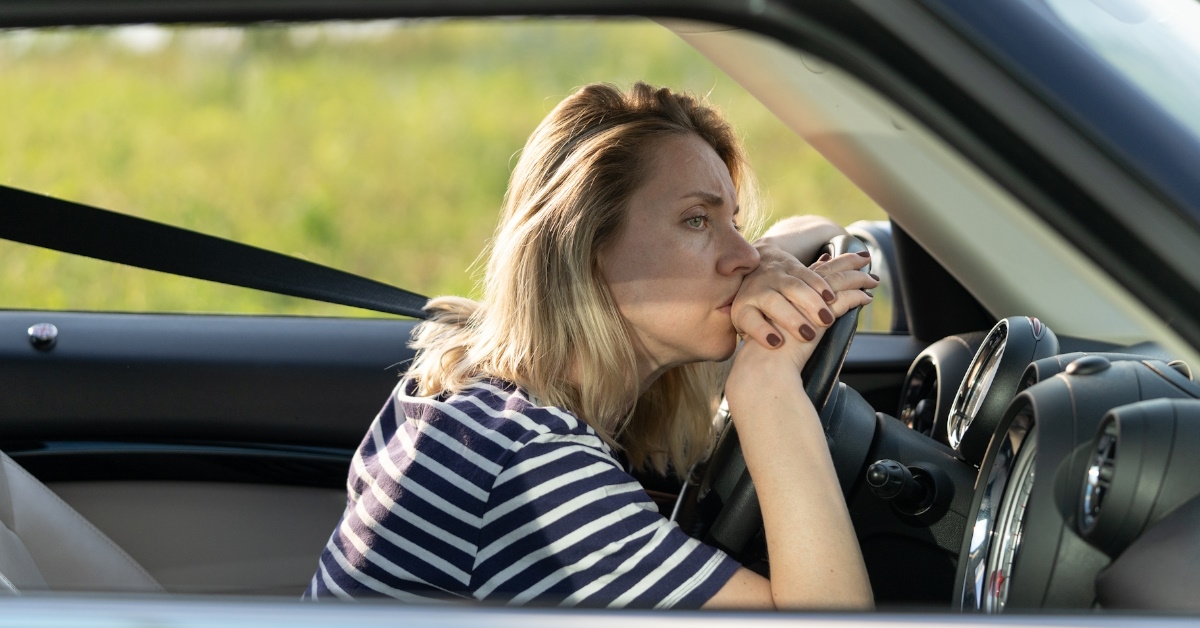 Middle aged women suffering from anxiety is lying on steering wheel frustrated,feeling scared to drive