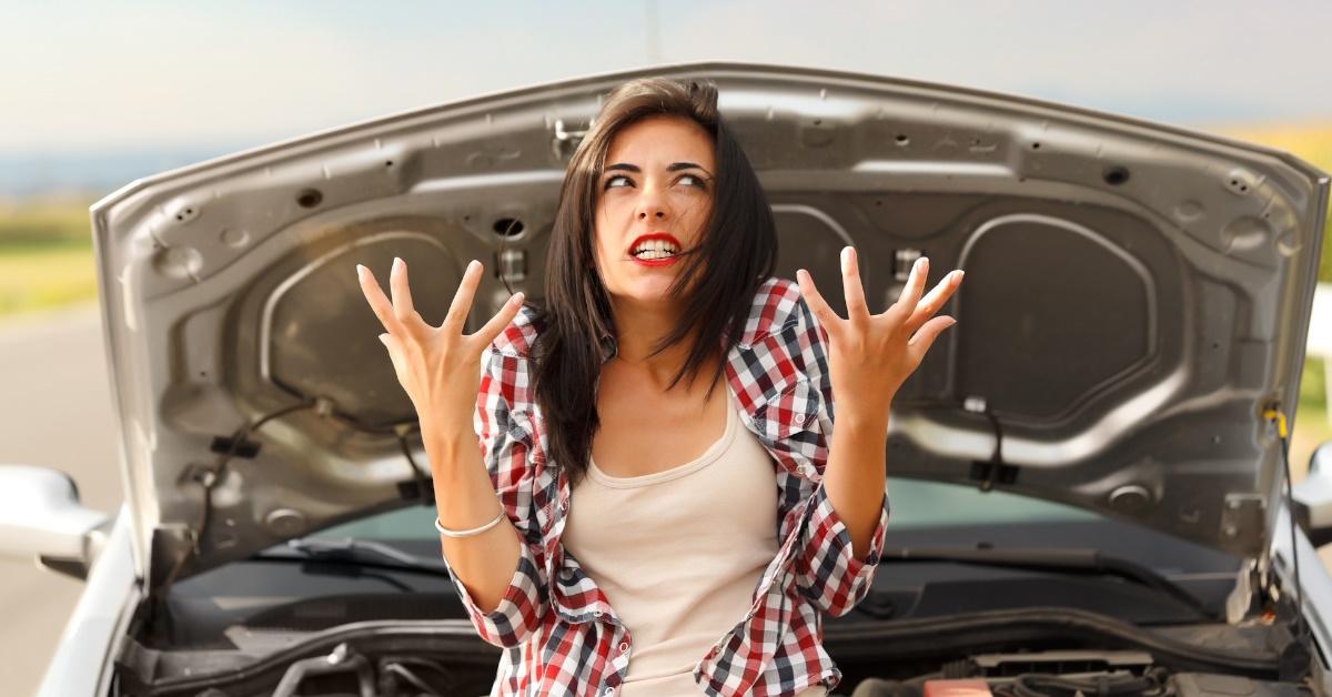 A young pensive women is getting mad at her out of order car