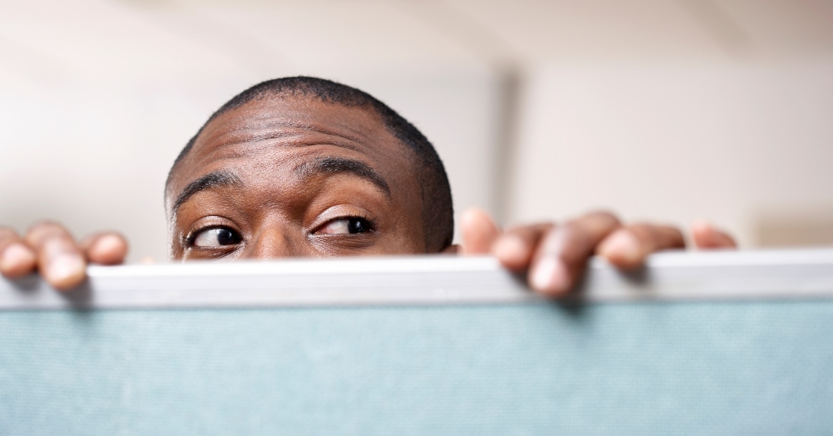 african american man peeking out of his office cabin at work