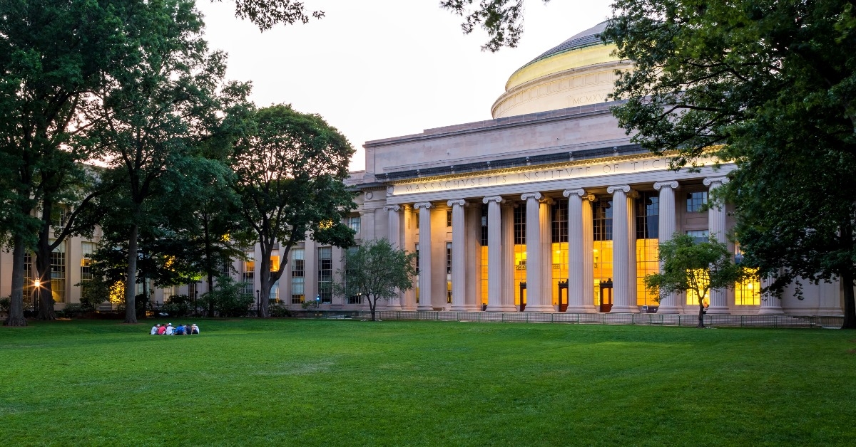 massachusetts institute of technology building with golden lights in front of garden full of grass and trees during day