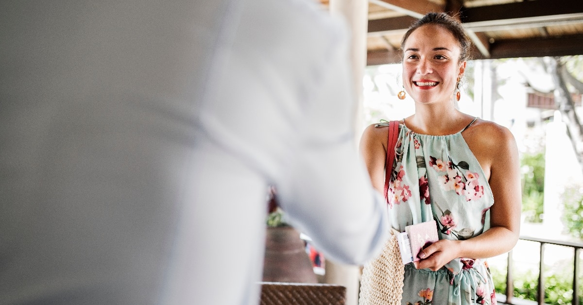 beautiful woman in day dress shaking hand with male receptionist after checking in